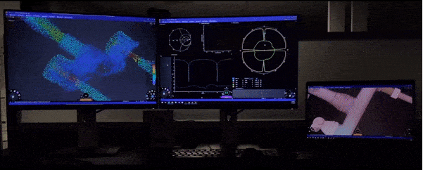 GIF animation of an office-setup of three screens showing Ansys Discovery application with CAD models, simulation results and data visualization